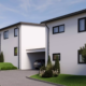 Moderne Außenansicht eines Neubauhauses mit Carport und geparktem Auto in Arnoldstein